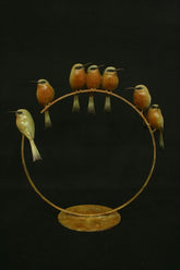 Decorative bronze art with birds on a ring against a black background