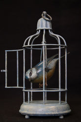 Bronze birdcage with a bird inside on a black background