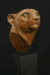 Bronze sculpture of a cheetah head on a black base on black background