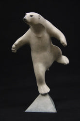 sculpture of white polar bear balancing on a triangle base.