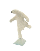 white polar bear balancing on one foot on a triangle base.