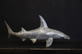 Bronze sculpture of a shark on a granite base and dark background