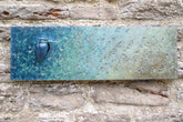 Bronze textured plaque with a blue bird on a stone wall