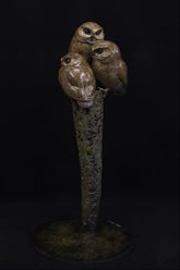 three small bronze owls perched on a branch sculpture