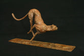 Bronze sculpture of a dynamic cheetah on a dark background