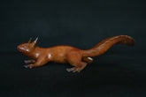 Bronze sculpture of a red squirrel on a black background