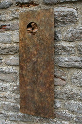 Bronze rust-colored metal plaque sculpture with a circular cutout with birds on a stone wall