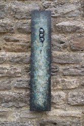 Decorative bronze panel with three birds on a stone wall