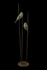 Decorative sculpture of two birds perched on tall thin rods with a dark background