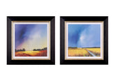Two framed landscape paintings shown side by side on a white background. Each black frame contains a white mat and a gold inner trim, with the artwork depicting a field under a dramatic blue and purple sky.