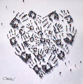 Large group of people forming a heart shape on a snowy ground.