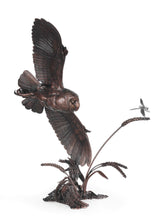 Bronze sculpture of an owl in flight with a dragonfly on a white background