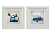 Two framed art prints displayed side by side on a white background. The left print shows a retro teal rotary telephone with white cartoon ears on a pale pink background.