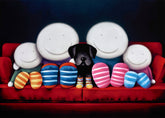 Black dog sitting on a red couch with four smiling face cushions and colorful socks.