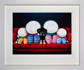 Framed artwork of a black dog sitting on a red couch with four white faces wearing colorful shoes.