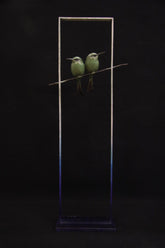 Two green birds perched on a branch against a black background