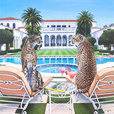 Two cheetahs on lounge chairs by a pool with a mansion in the background