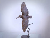 Bronze sculpture of a bird in flight on a white background