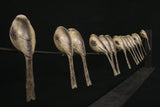 Set of 14 bird sculptures arranged in a row on a wire on a black background