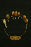 Decorative bronze art with birds on a ring against a black background