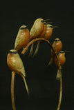 Decorative bronze birds on a branch ring against a black background