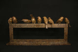 Bronze sculpture of birds perched on a sculptural form against a black background