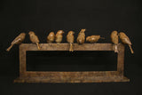 Bronze sculpture of birds perched on a sculptural form against a black background