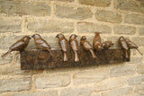 Bronze sculpture of birds on a sculptural form on a stone wall