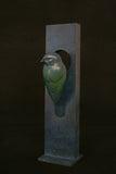 Decorative bird sculpture on a rectangular base against a dark background