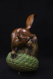 Bronze sculpture of a squirrel on an acorn against a black background