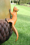 Large sculpture of an acorn with two small squirrels on top, set against a garden backdrop.