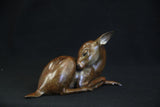 Bronze sculpture of a young deer on a black background