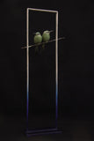 Two green birds perched on a branch against a black background