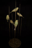 Bronze sculpture of five birds on a stand against a black background