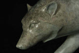 Bronze sculpture of grey wolf head against a black background.