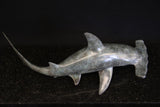 Bronze sculpture of a shark on a granite base and dark background