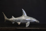 Bronze sculpture of a shark on a granite base and dark background