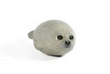 Bronze sculpture of seal pup laying on a white background