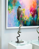 Decorative sculpture of a bird on a spiral base in front of a colourful abstract painting.