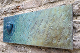 Bronze textured plaque with a blue bird on a stone wall