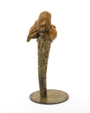 Bronze sculpture of three owls on a branch with a white background