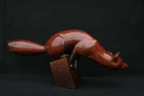 Bronze sculpture of red fox balancing on a small block base.