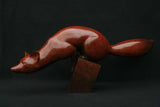 Bronze sculpture of red fox balancing on a small block base.