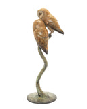 Bronze sculpture of two owls perched on a curved branch on a white background
