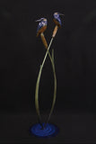 Bronze sculpture of two kingfisher birds on a plant-like structure against a dark background