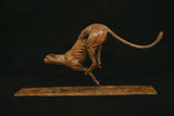 Bronze sculpture of a dynamic cheetah on a dark background