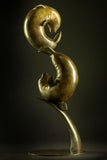 Bronze sculpture of two seals interacting on a dark background