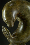 Bronze sculpture of two seals interacting on a dark background
