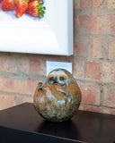 bronze sculpture of sloth on a surface with a brick wall background
