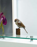 bronze sculpture of bird on a stand with a blurred background